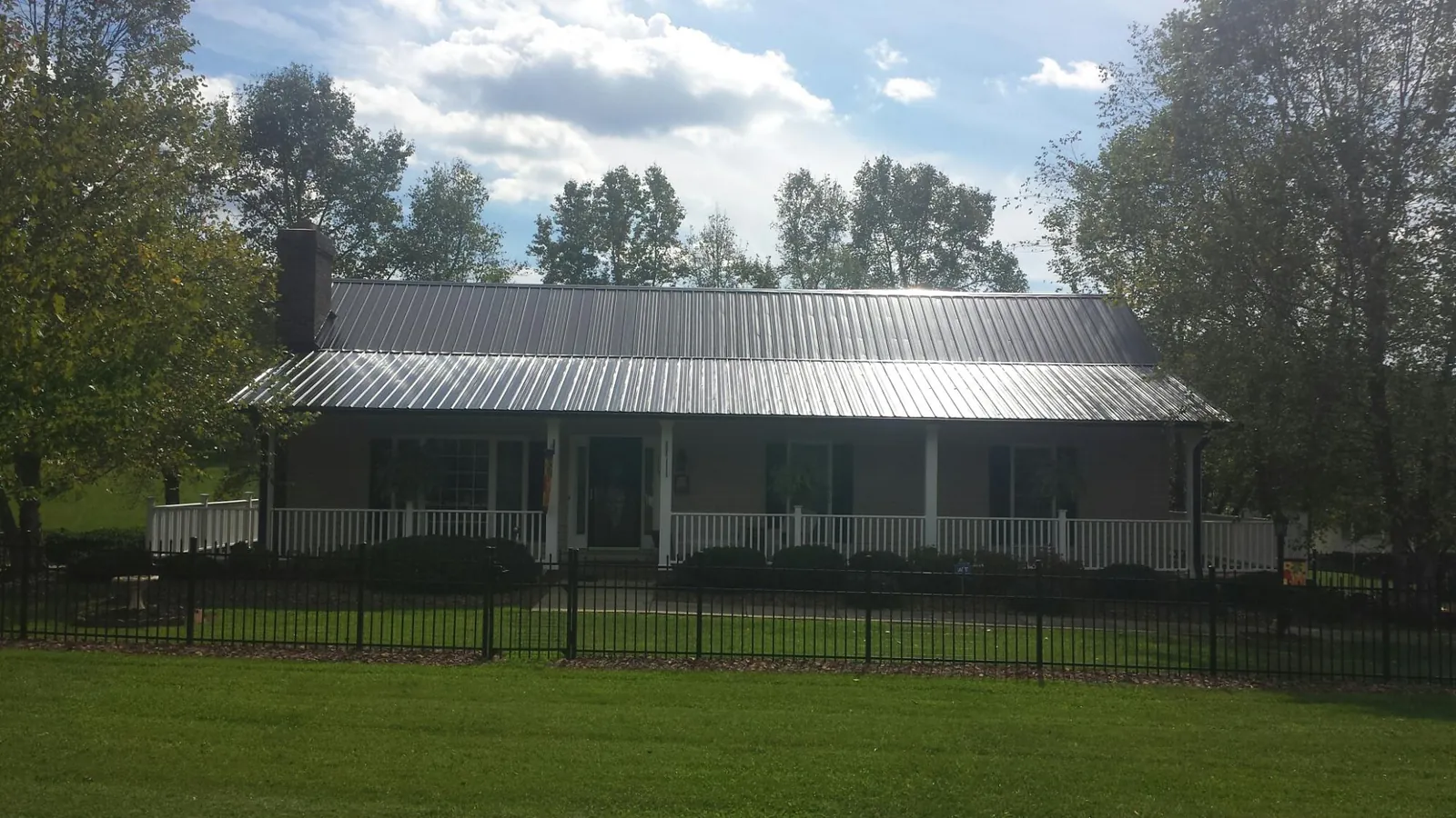 Gray metal roof on a brick ranch with a full width front porch — Gutter Guard Installation work by our crew in Mishicot