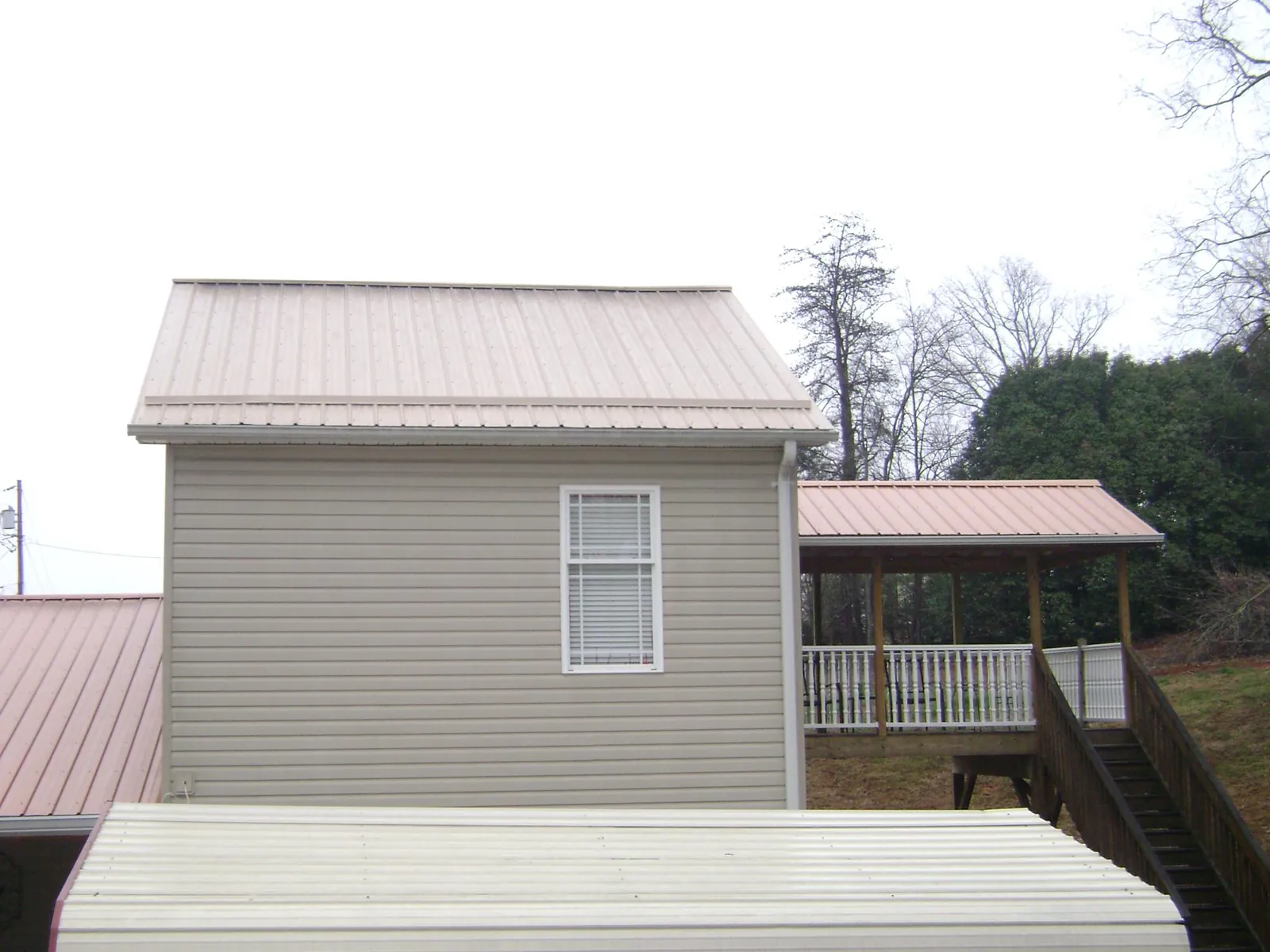 Tan metal roofs on a two story addition and attached porch, from a Roof Replacement job in Mishicot