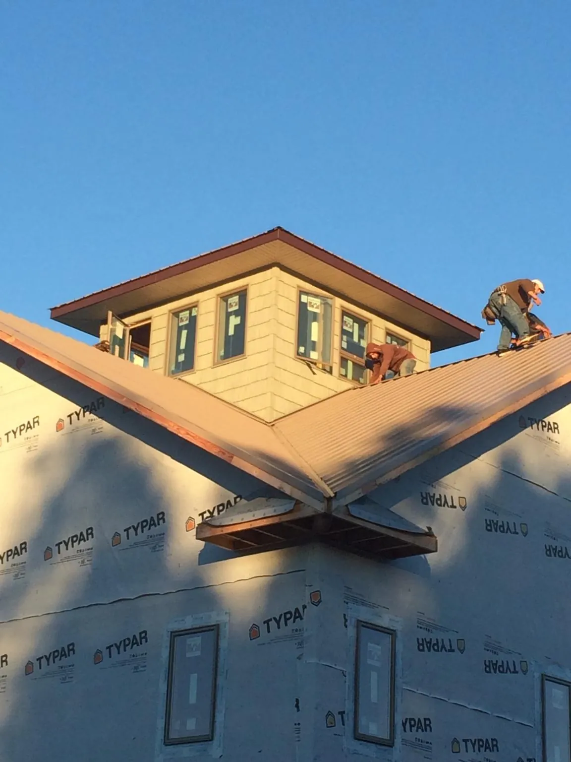 Roofers working around a rooftop cupola on a new metal roof at sunset — Roof Waterproofing in Mishicot by Roofing Brothers